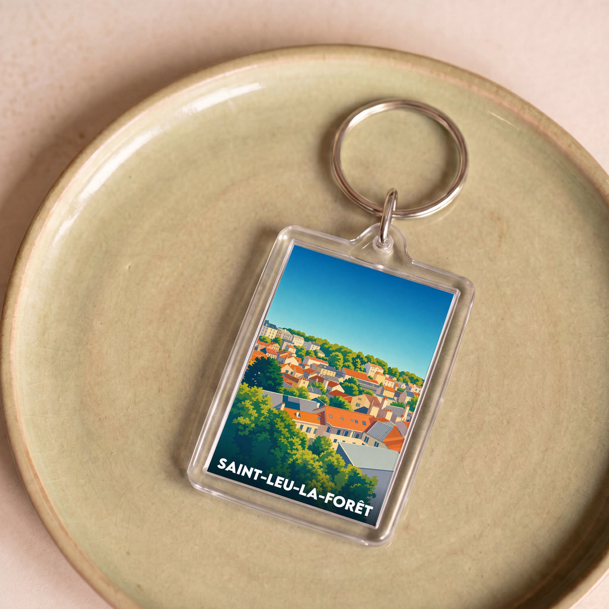 Porte-clés souvenir de la ville de Saint-Leu-la-Forêt avec une illustration stylisée.