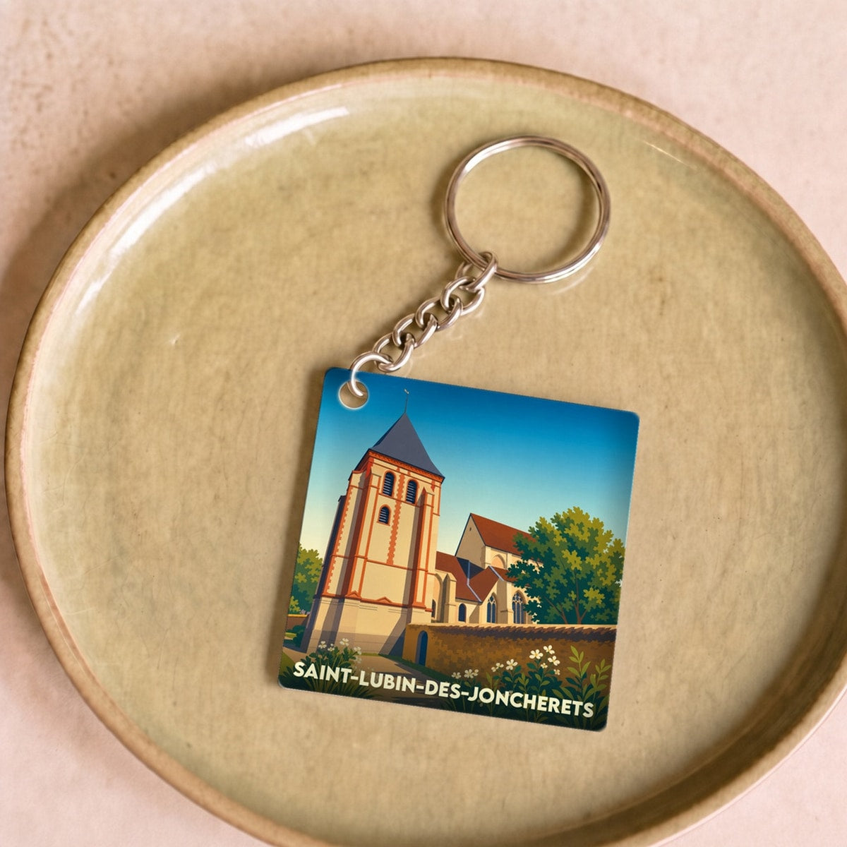 Porte-clés souvenir de la ville de Saint-Lubin-des-Joncherets avec une illustration stylisée de son église.