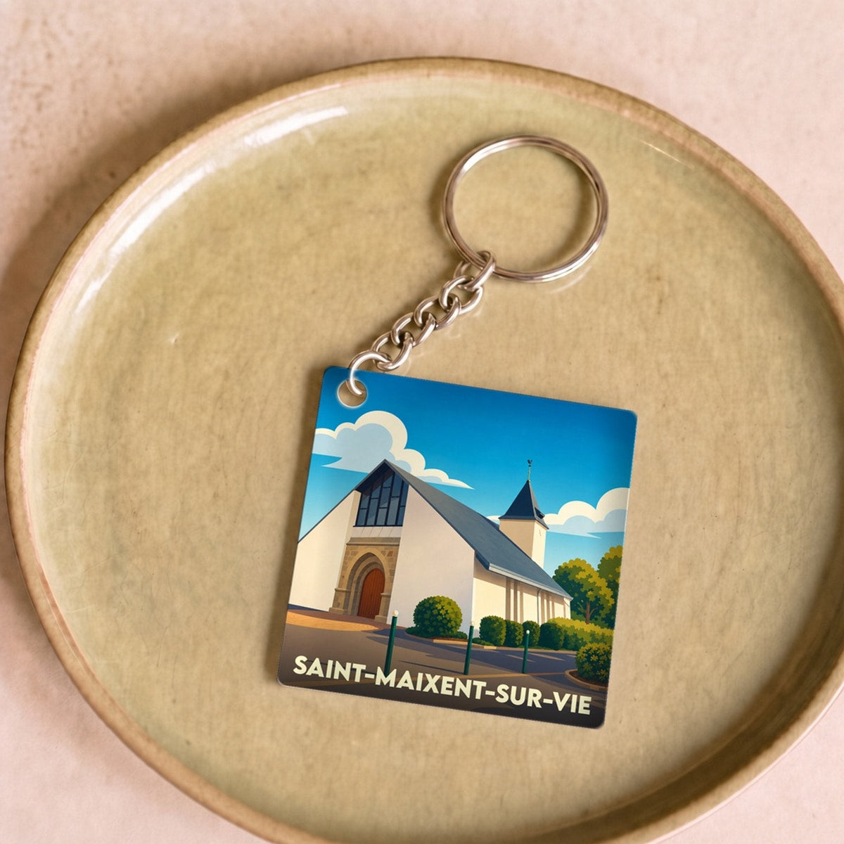 Porte-clés souvenir de la ville de Saint-Maixent-sur-Vie avec une illustration stylisée de son église.