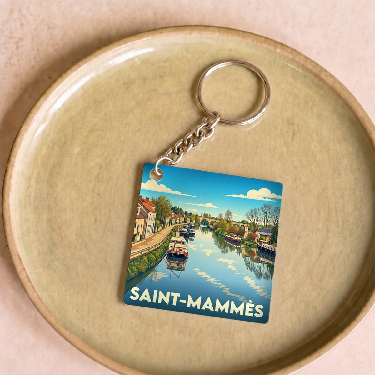Porte-clés souvenir de la ville de Saint-Mammès avec une illustration stylisée d'un canal et de péniches.
