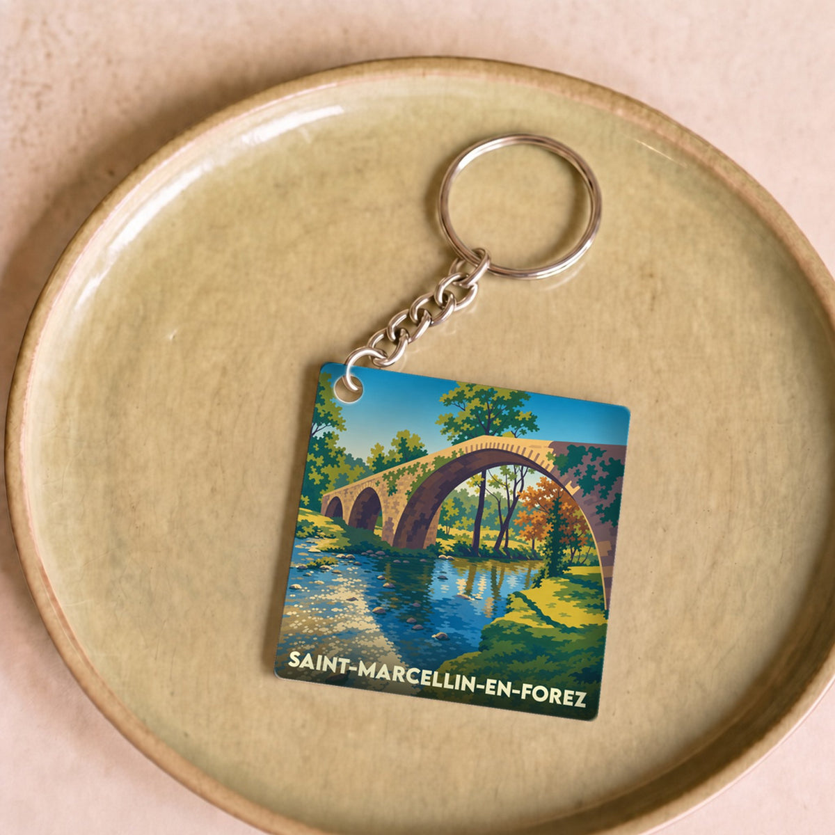 Porte-clés souvenir de la ville de Saint-Marcellin-en-Forez avec une illustration stylisée d'un pont en pierre.