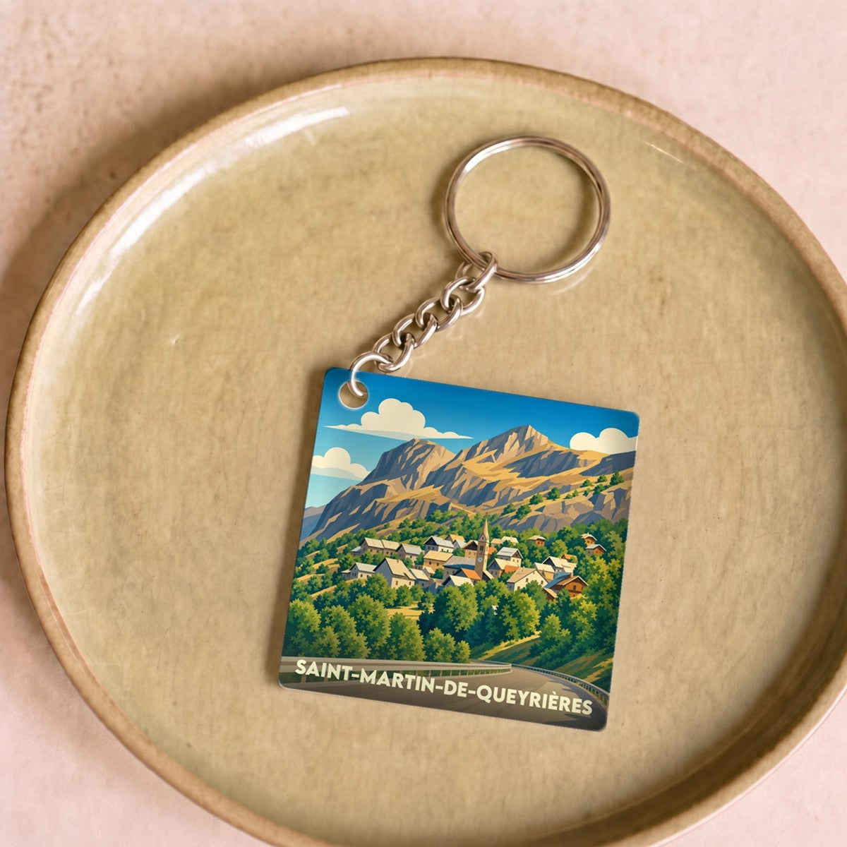 Porte-clés souvenir de la ville de Saint-Martin-de-Queyrières avec une illustration de paysage de montagne.
