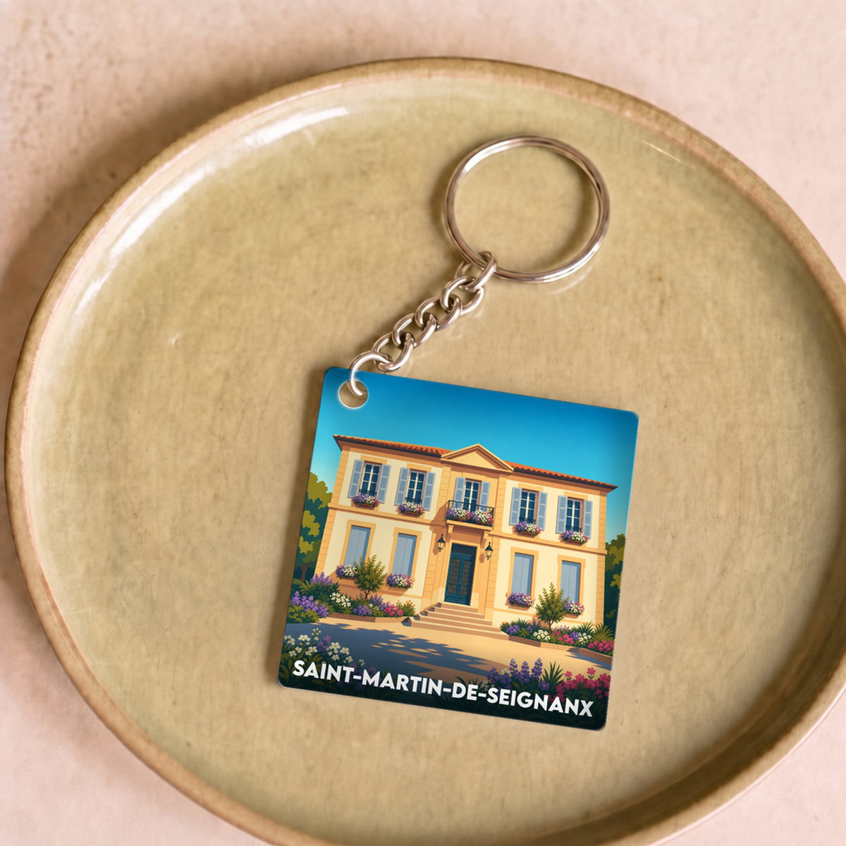 Porte-clés souvenir de la ville de Saint-Martin-de-Seignanx avec une illustration stylisée d'une maison landaise.