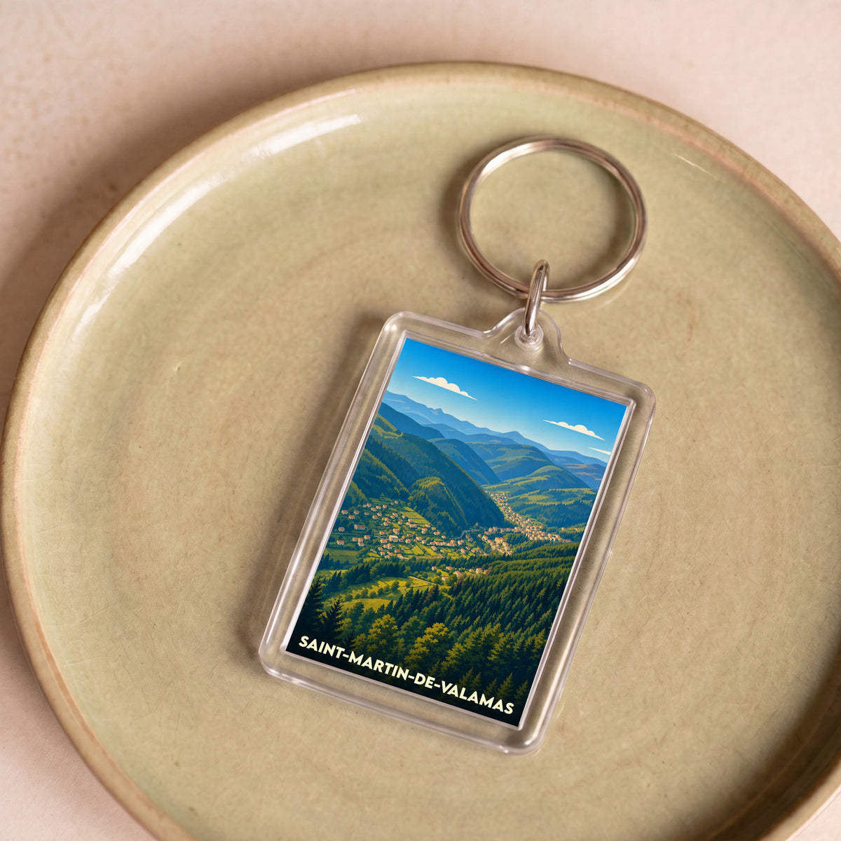 Porte-clés souvenir de la ville de Saint-Martin-de-Valamas avec une illustration stylisée d'un paysage de montagne.