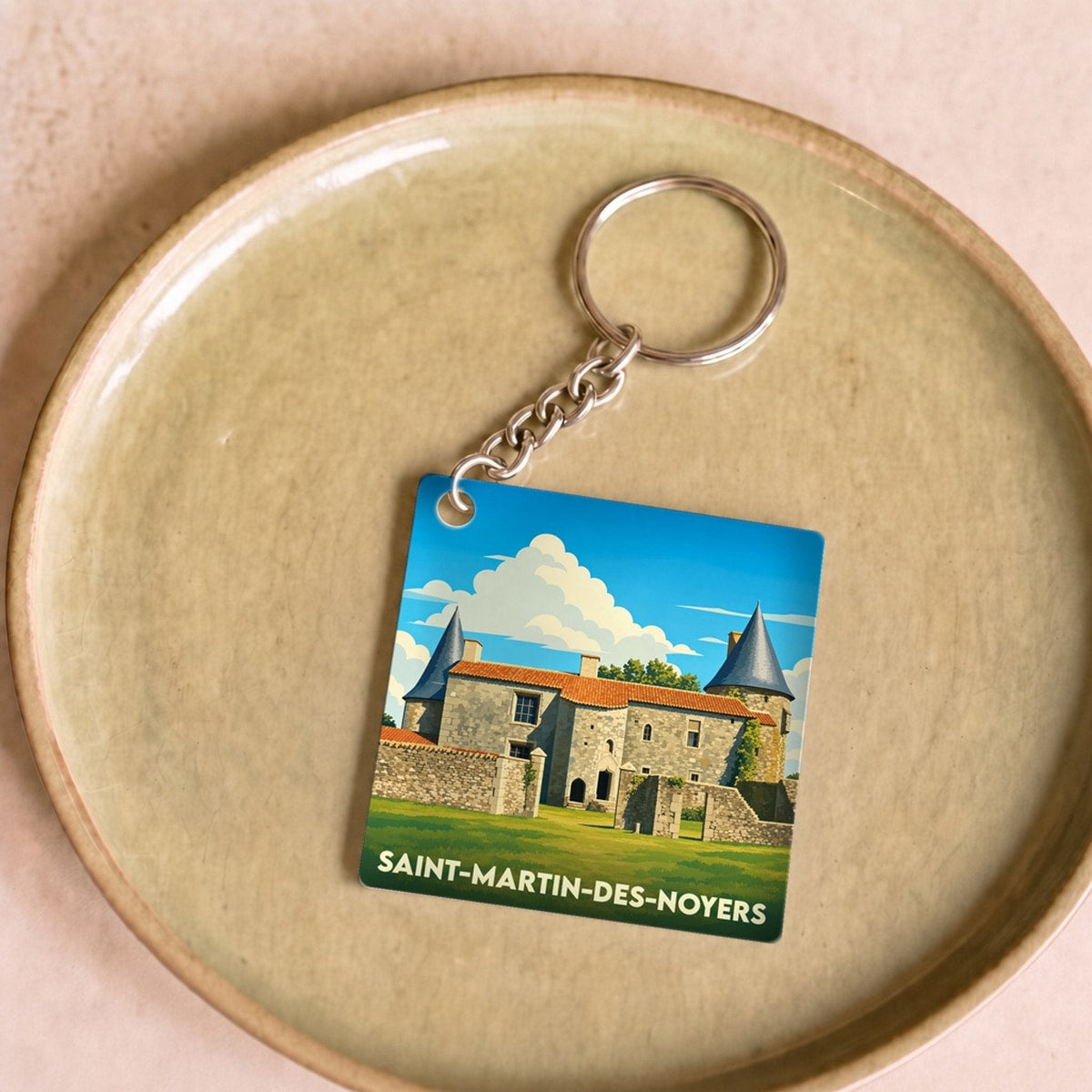 Porte-clés souvenir de la ville de Saint-Martin-des-Noyers avec une illustration stylisée de son château.