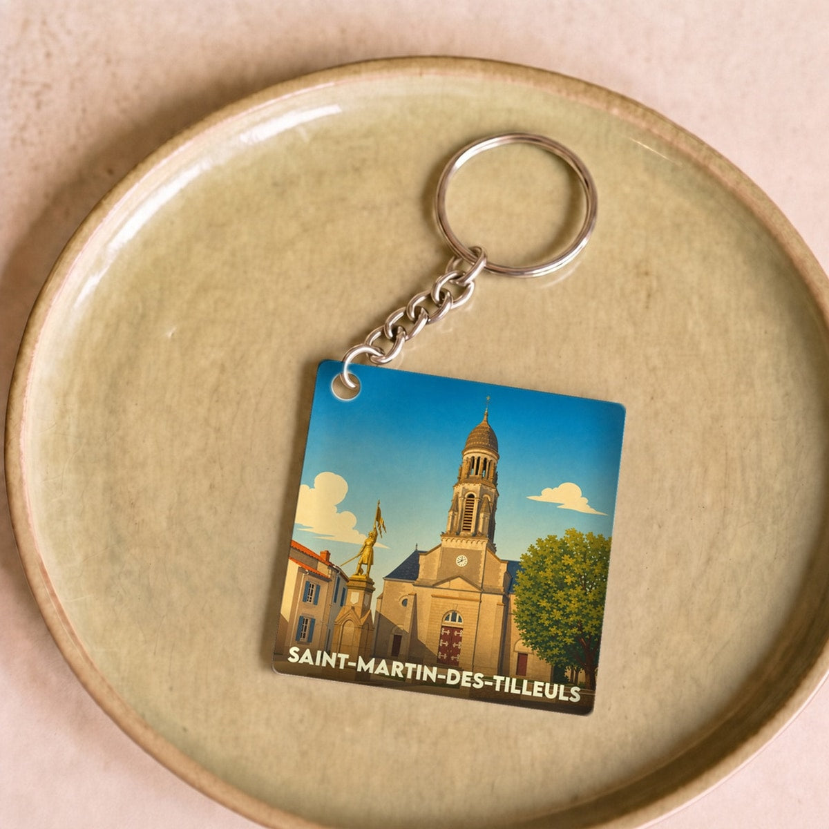 Porte-clés souvenir de la ville de Saint-Martin-des-Tilleuls avec une illustration stylisée.
