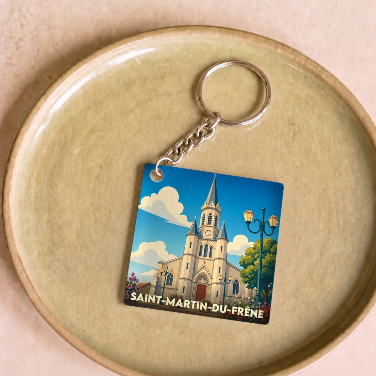 Porte-clés souvenir de la ville de Saint-Martin-du-Frêne avec une illustration stylisée de son église.