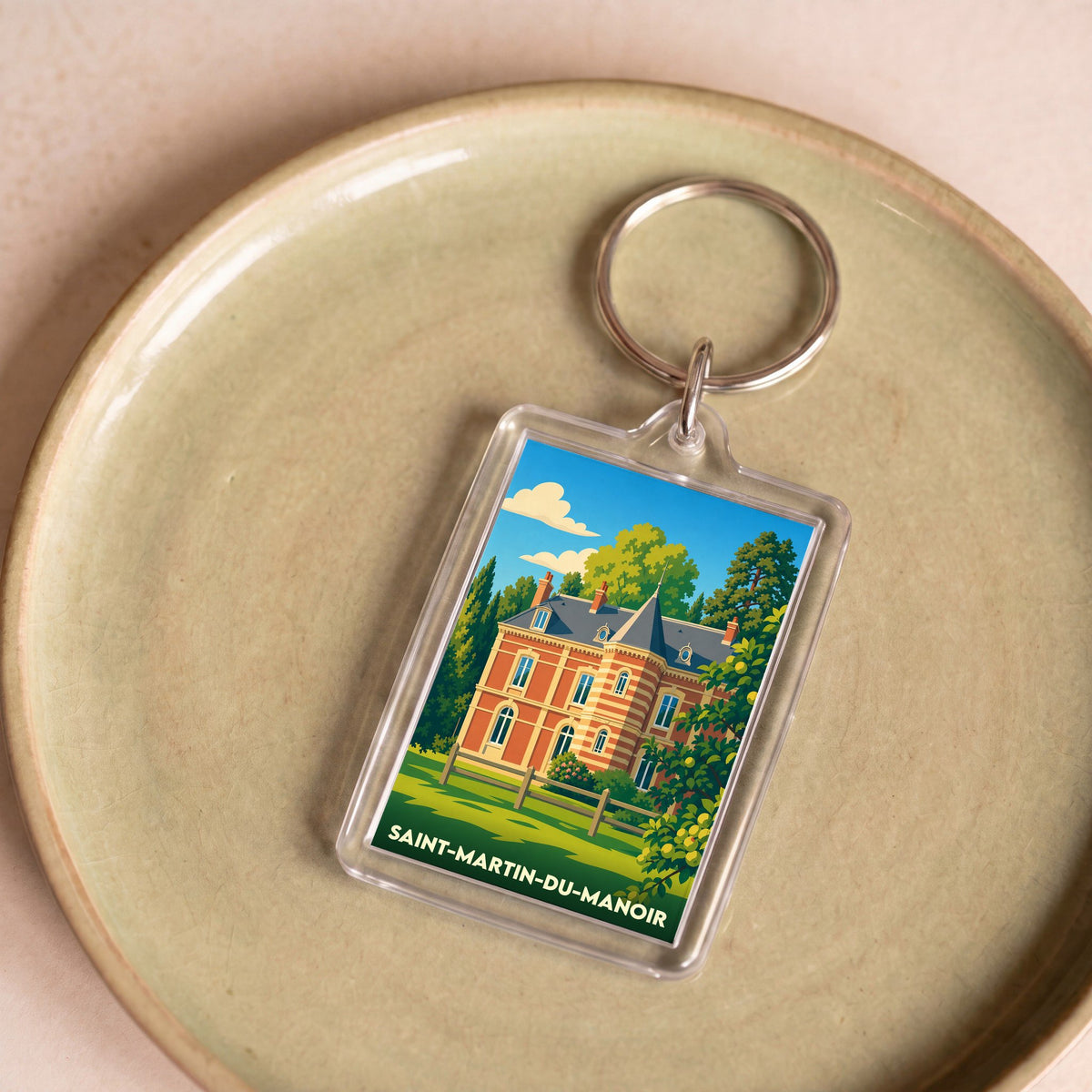 Porte-clés souvenir de la ville de Saint-Martin-du-Manoir avec une illustration stylisée d'un manoir.