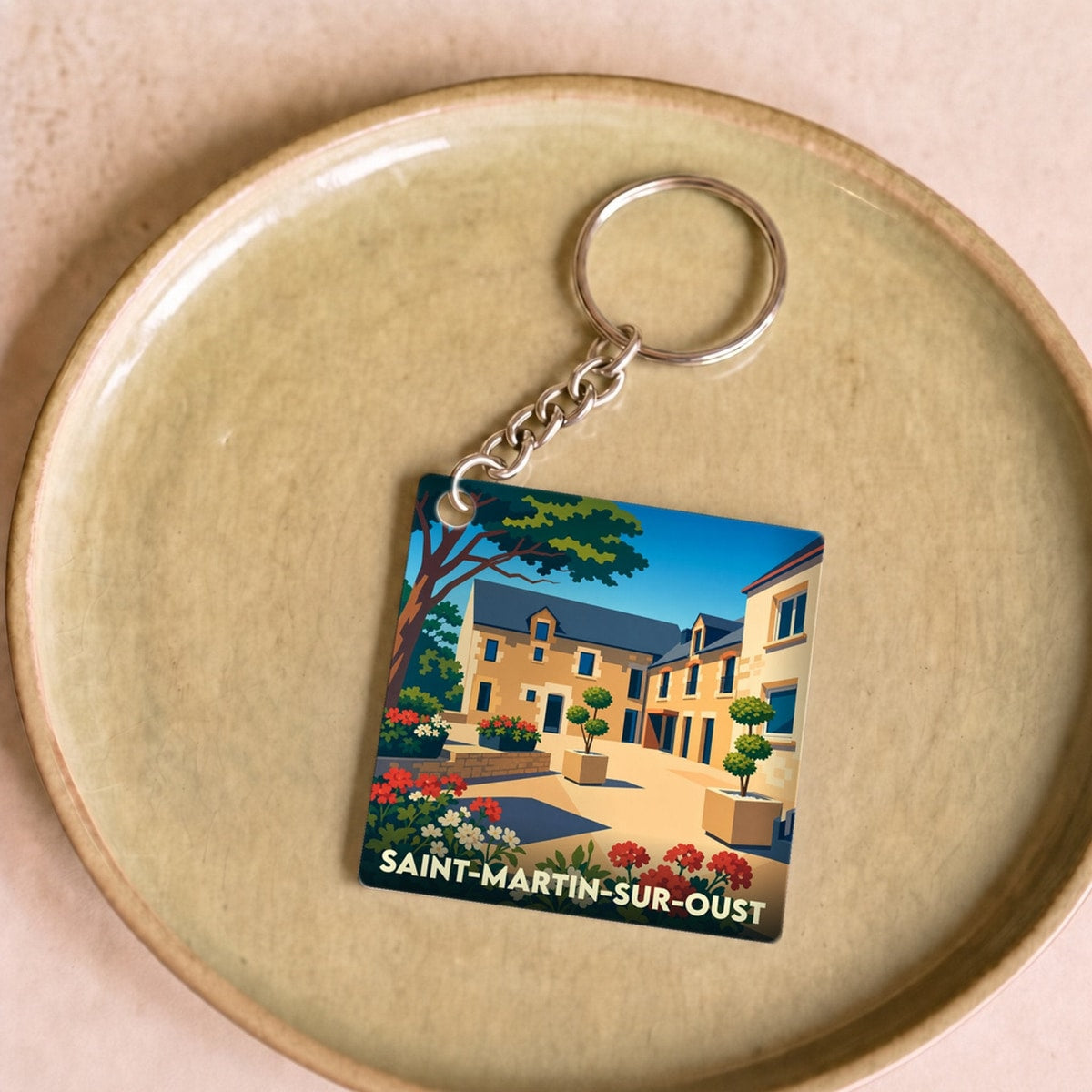 Porte-clés souvenir de la ville de Saint-Martin-sur-Oust avec une illustration stylisée d'un village fleuri.