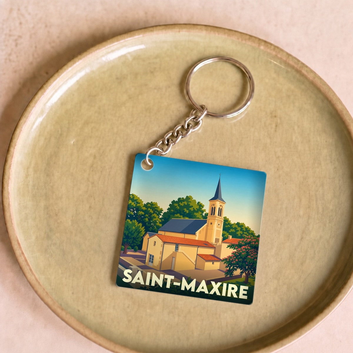 Porte-clés souvenir de la ville de Saint-Maxire avec une illustration stylisée de son église.