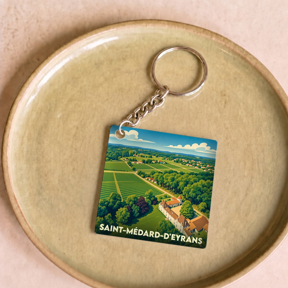 Porte-clés souvenir de la ville de Saint-Médard-d'Eyrans avec une illustration paysagère stylisée.