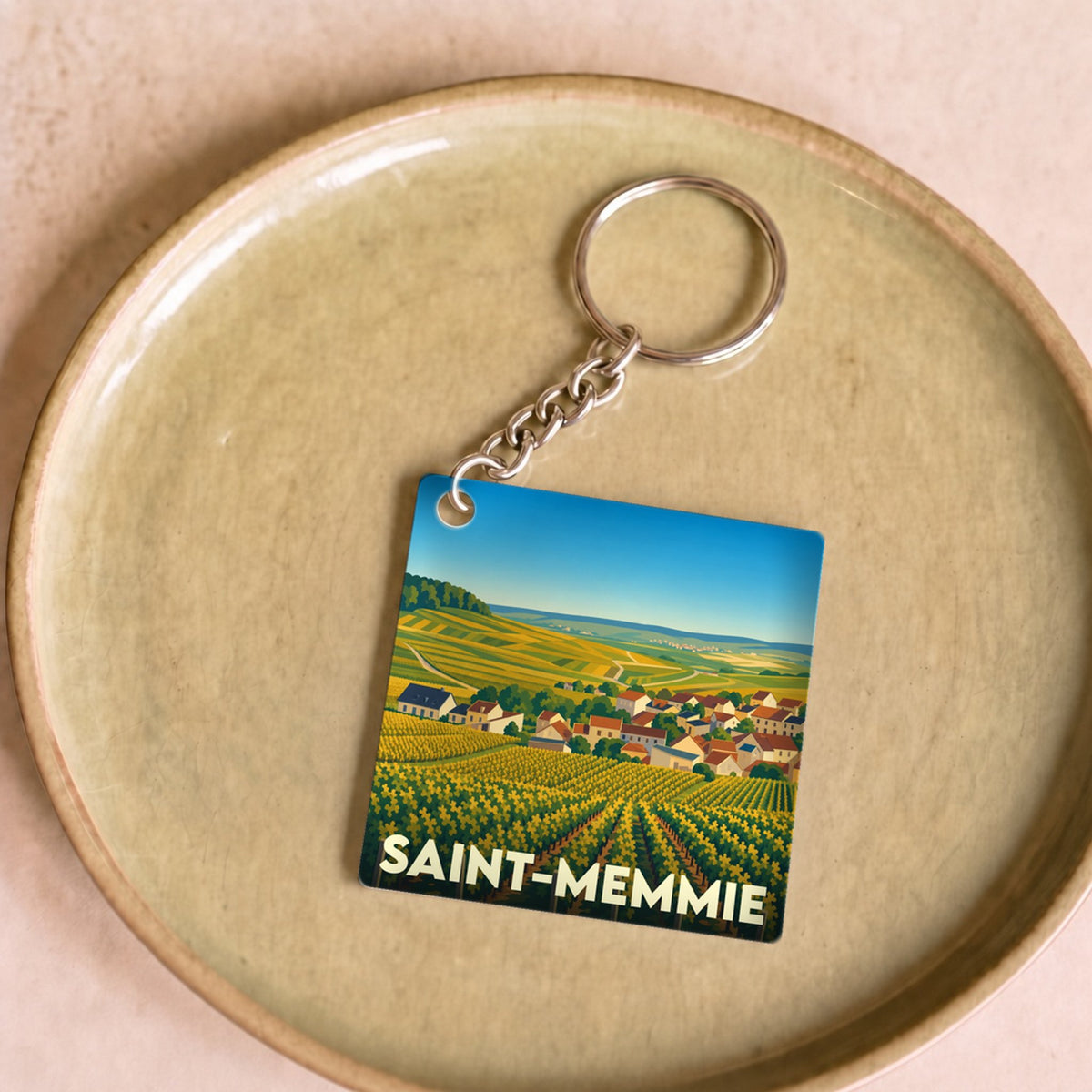 Porte-clés souvenir de la ville de Saint-Memmie avec une illustration stylisée de vignobles.
