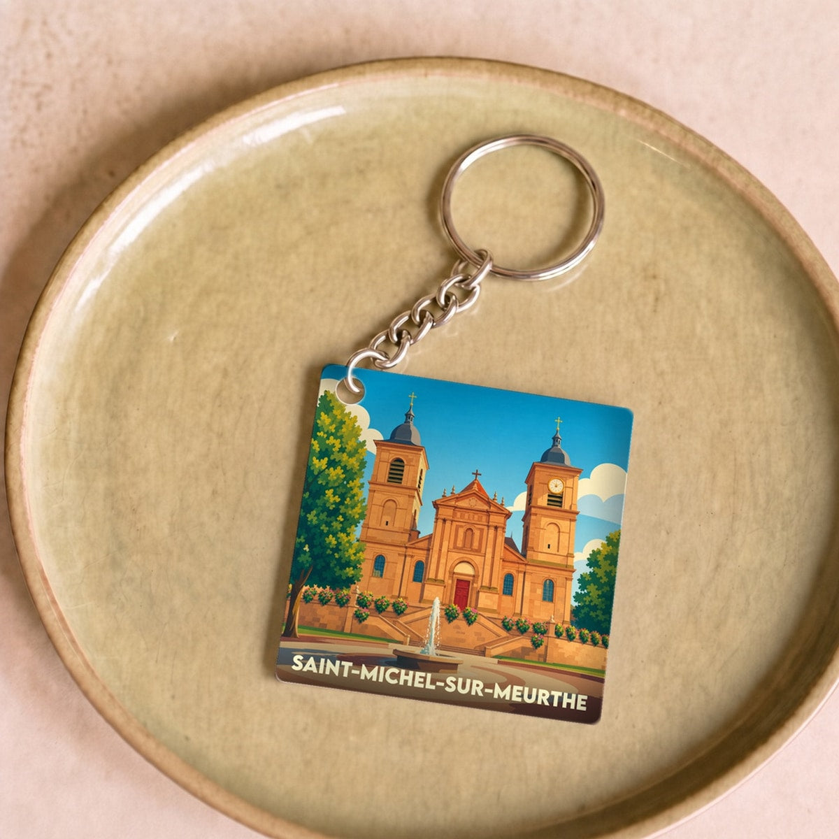 Porte-clés souvenir de la ville de Saint-Michel-sur-Meurthe avec une illustration stylisée de son église et d'une fontaine.