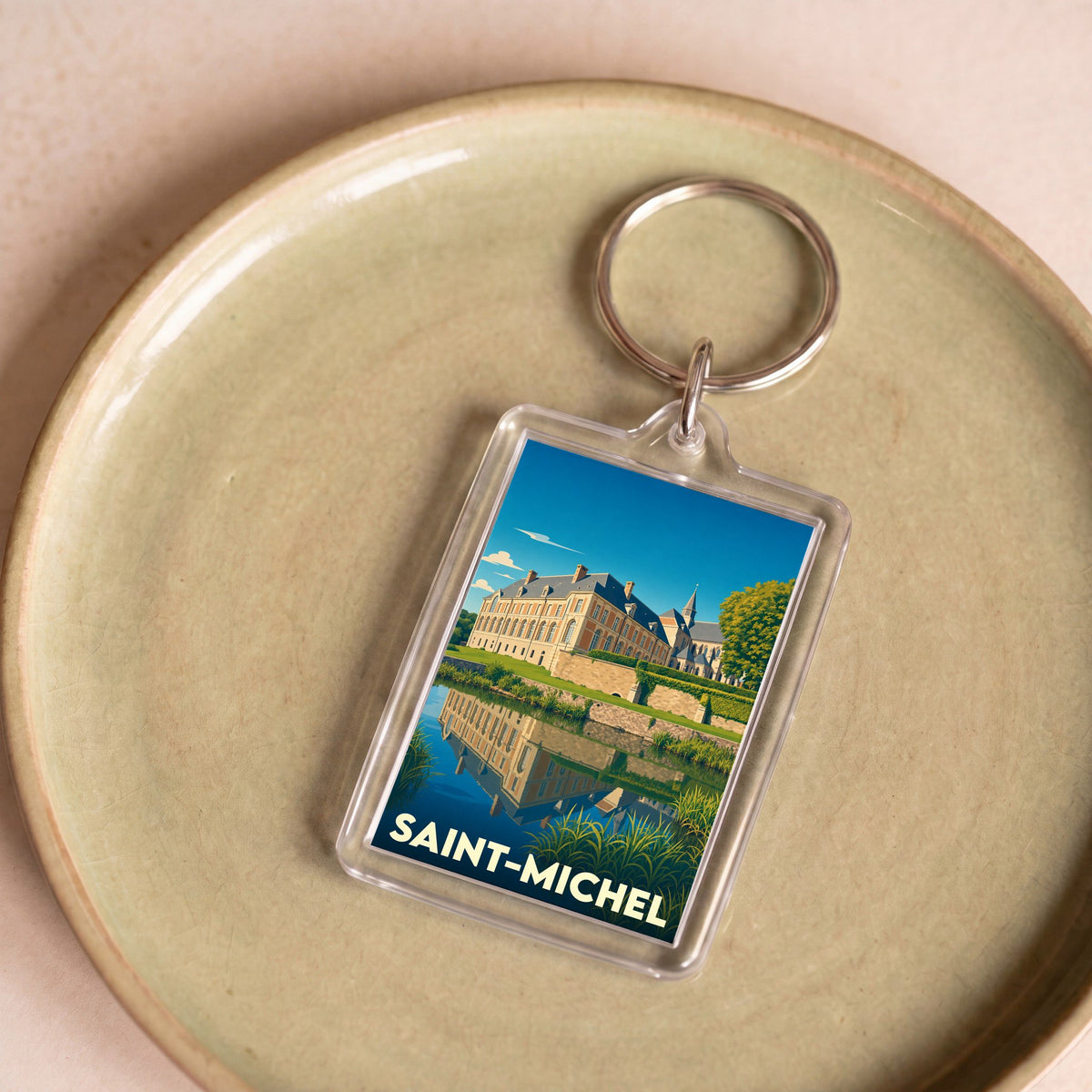 Porte-clés souvenir de la ville de Saint-Michel avec une illustration stylisée d'un château se reflétant dans l'eau.