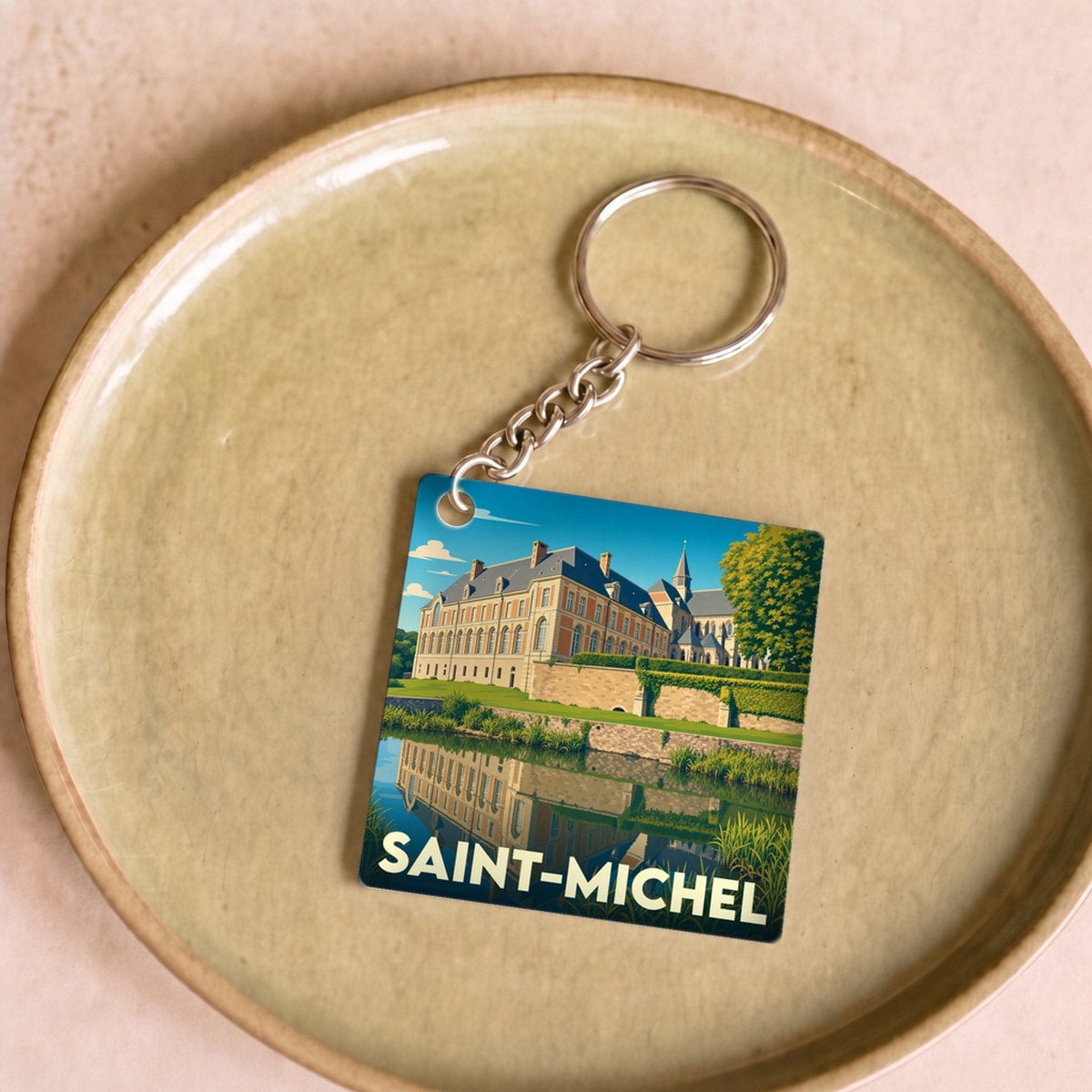 Porte-clés souvenir de la ville de Saint-Michel avec une illustration stylisée d'un château se reflétant dans l'eau.