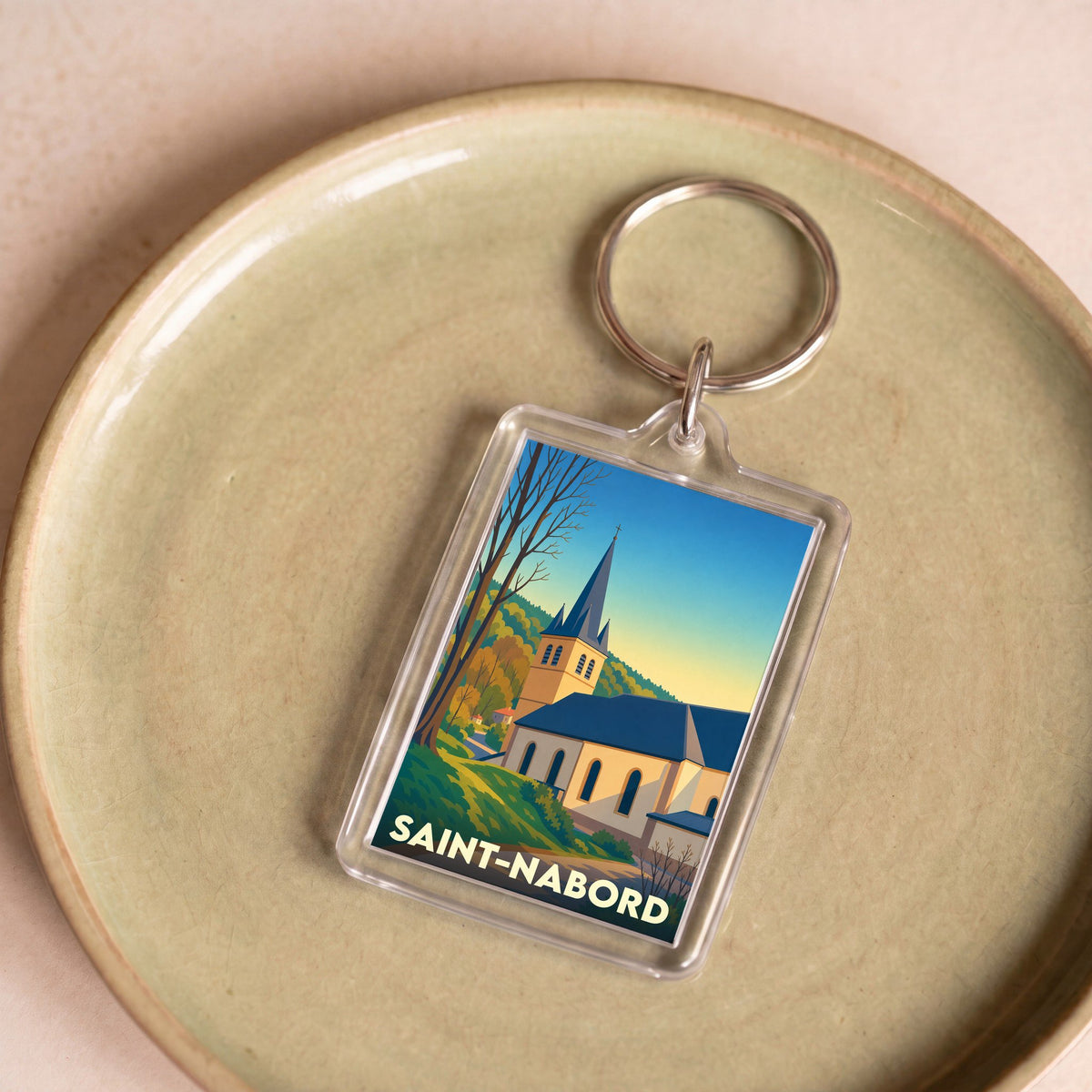 Porte-clés souvenir de la ville de Saint-Nabord avec une illustration stylisée de son église.