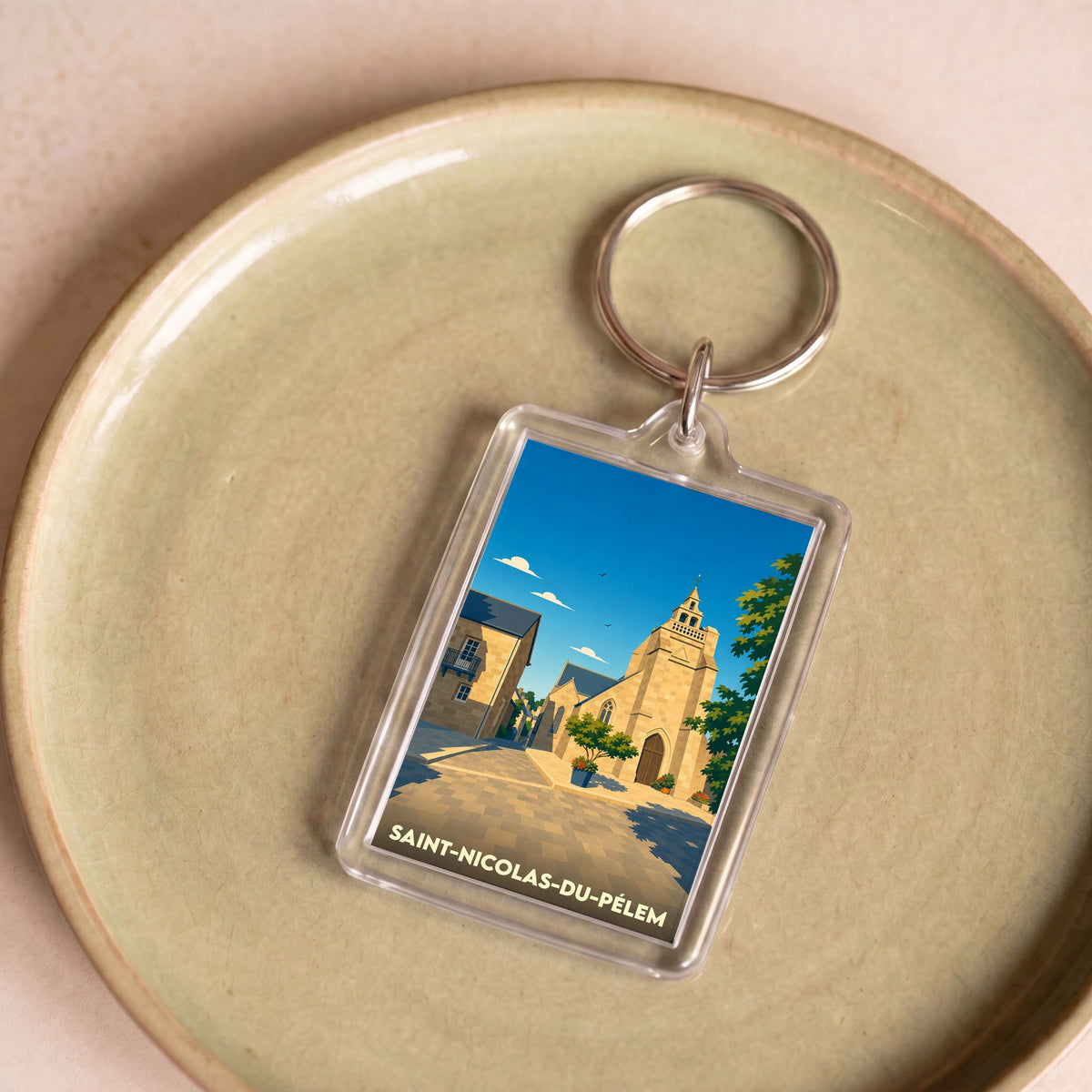 Porte-clés souvenir de la ville de Saint-Nicolas-du-Pélem avec une illustration stylisée de son église.