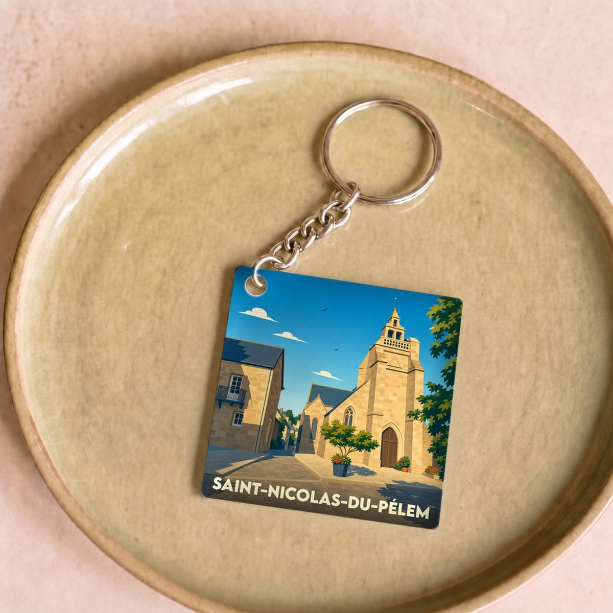 Porte-clés souvenir de la ville de Saint-Nicolas-du-Pélem avec une illustration stylisée de son église.