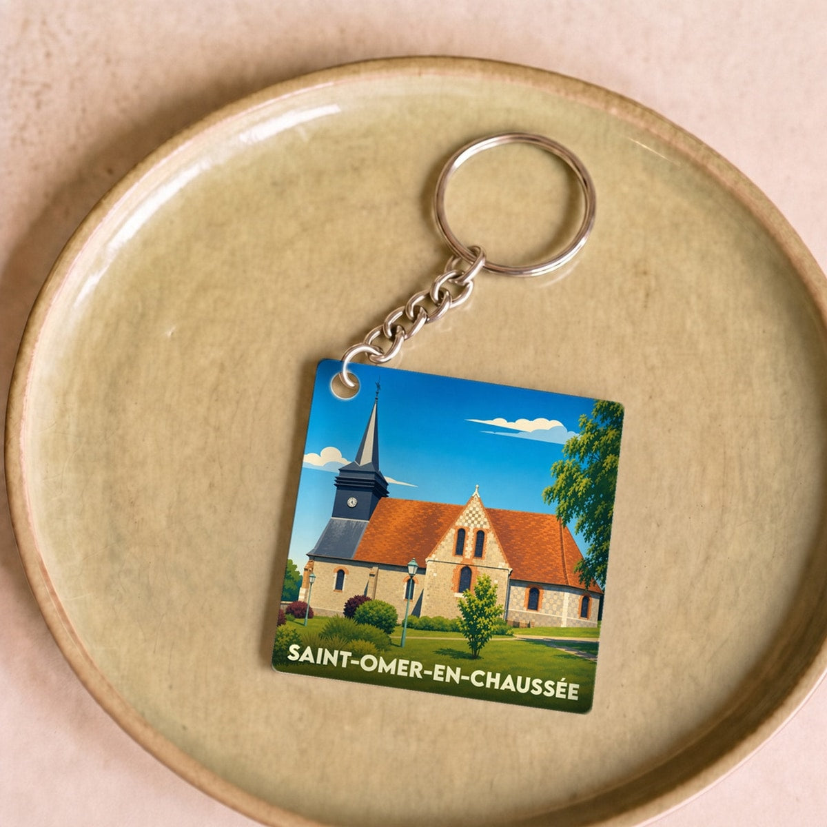 Porte-clés souvenir de la ville de Saint-Omer-en-Chaussée avec une illustration stylisée de son église.