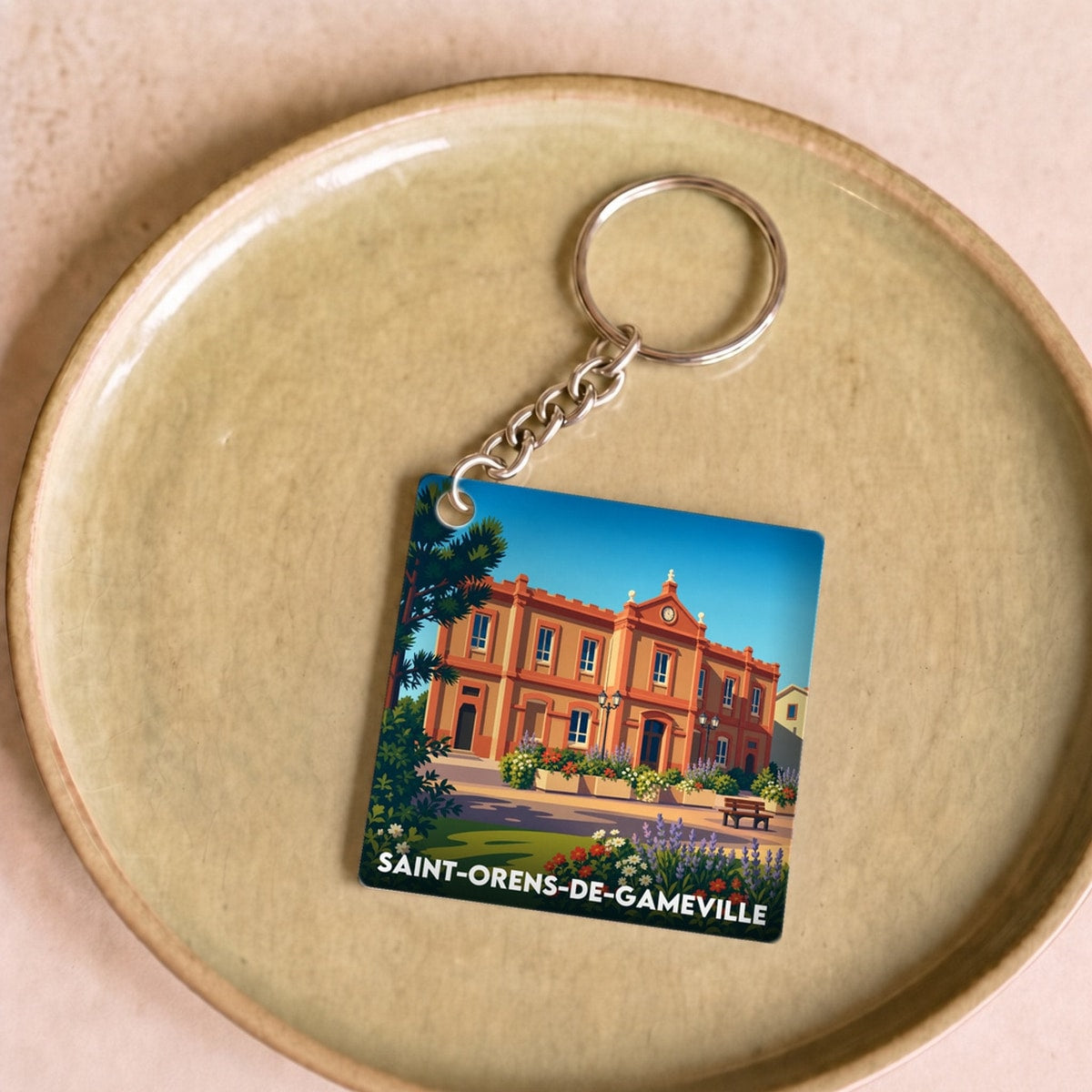Porte-clés souvenir de la ville de Saint-Orens-de-Gameville avec une illustration stylisée.