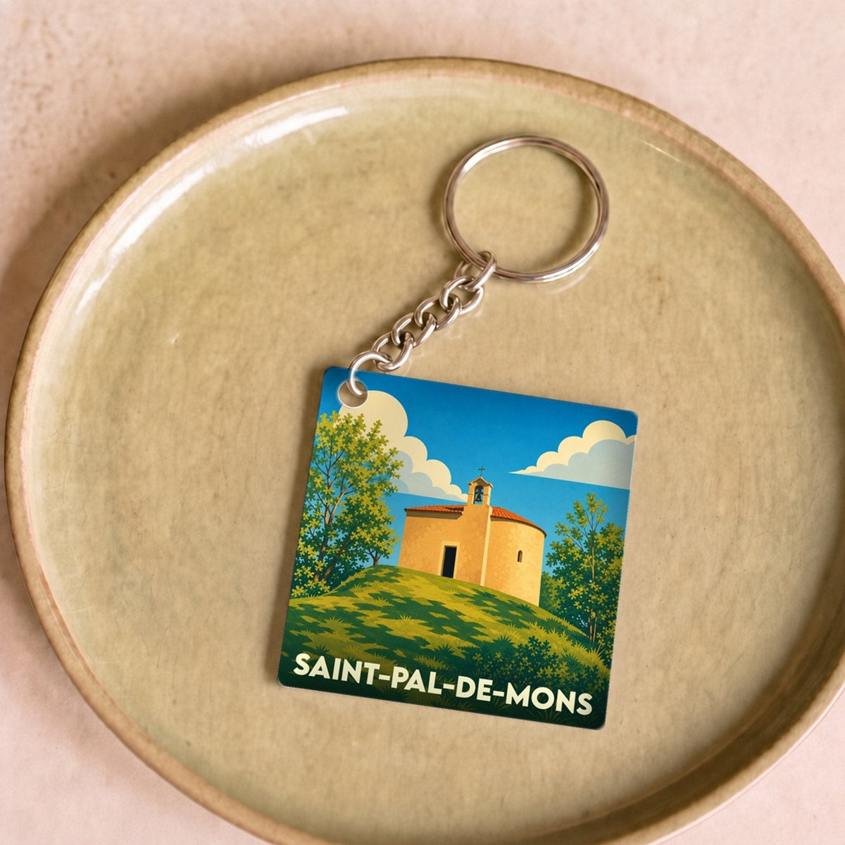 Porte-clés souvenir de la ville de Saint-Pal-de-Mons avec une illustration stylisée d'une chapelle sur une colline.
