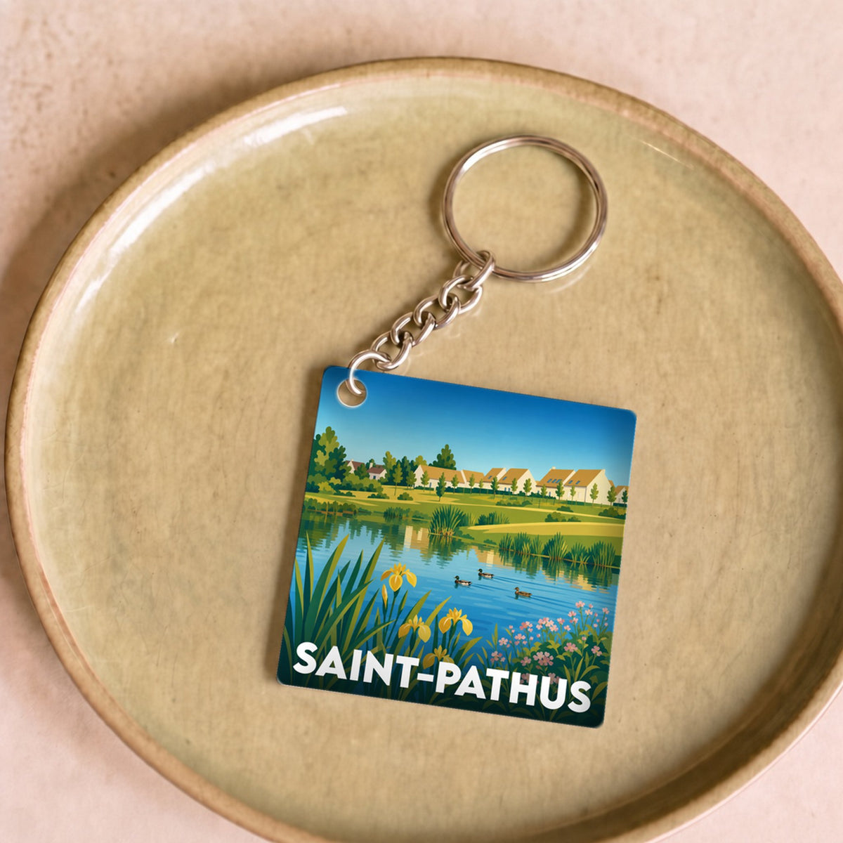 Porte-clés souvenir de la ville de Saint-Pathus avec une illustration stylisée d'un paysage lacustre.