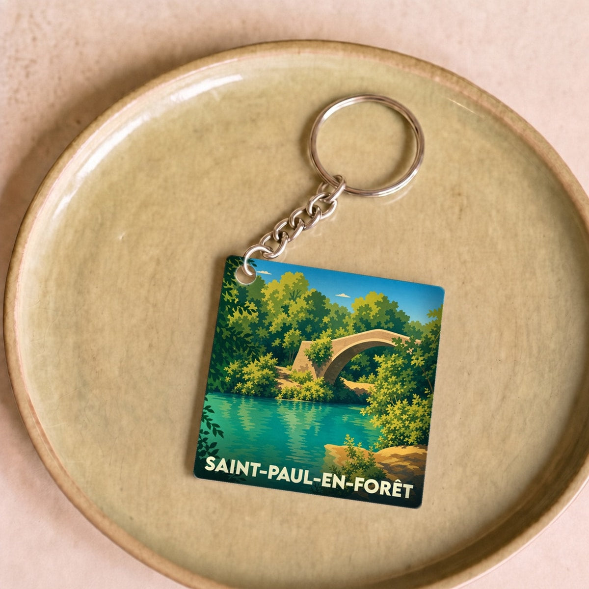 Porte-clés souvenir de la ville de Saint-Paul-en-Forêt avec une illustration stylisée d'un pont en pierre.