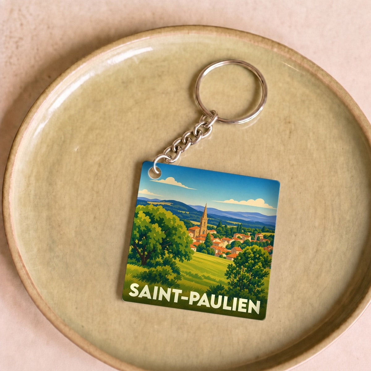 Porte-clés souvenir de la ville de Saint-Paulien avec une illustration paysagère stylisée.