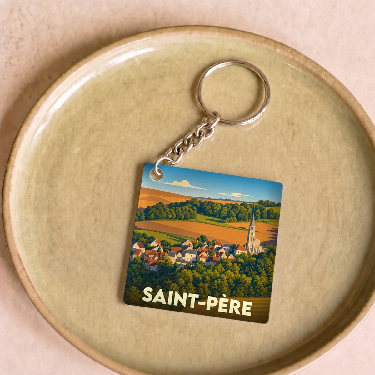 Porte-clés souvenir de la ville de Saint-Père avec une illustration stylisée d'un paysage rural.