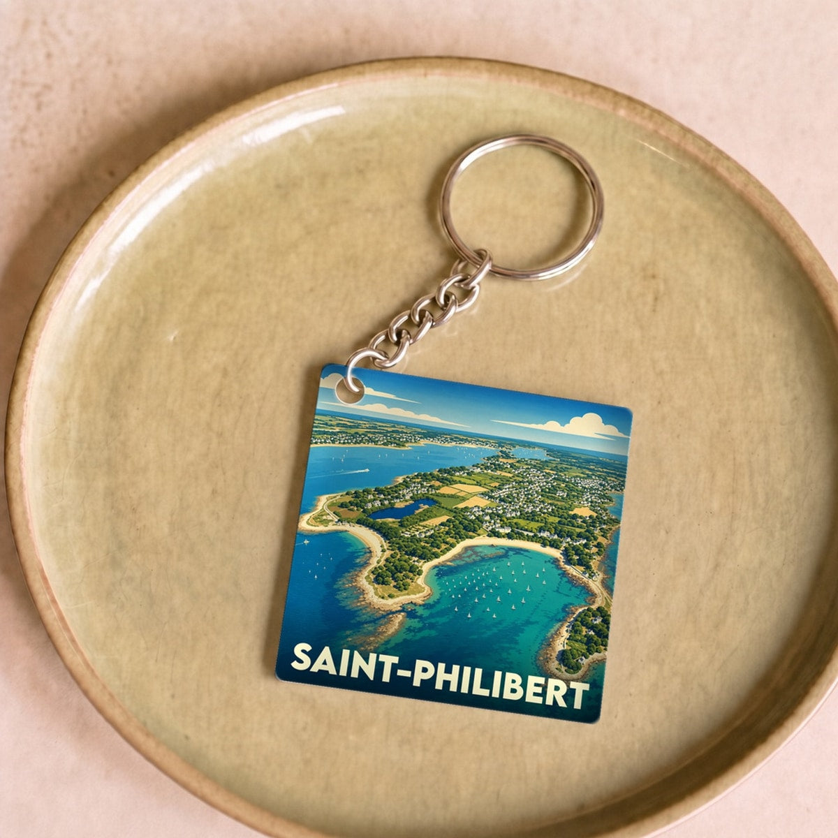 Porte-clés souvenir de la ville de Saint-Philibert avec une illustration stylisée d'un paysage côtier vu du ciel.