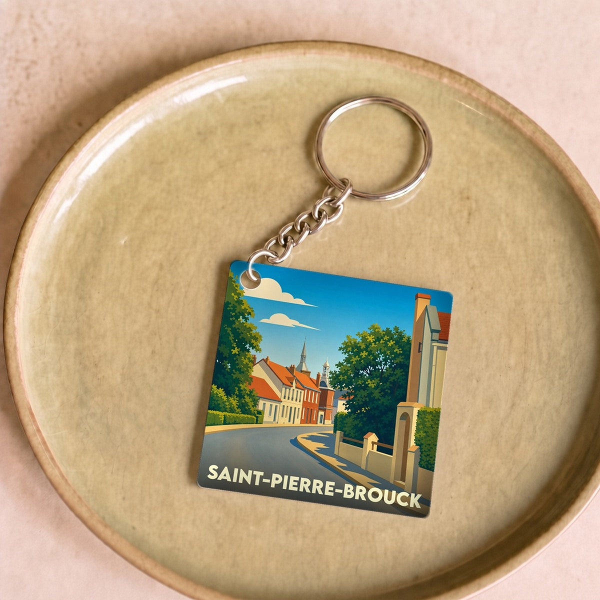Porte-clés souvenir de la ville de Saint-Pierre-Brouck avec une illustration stylisée d'une rue pittoresque.