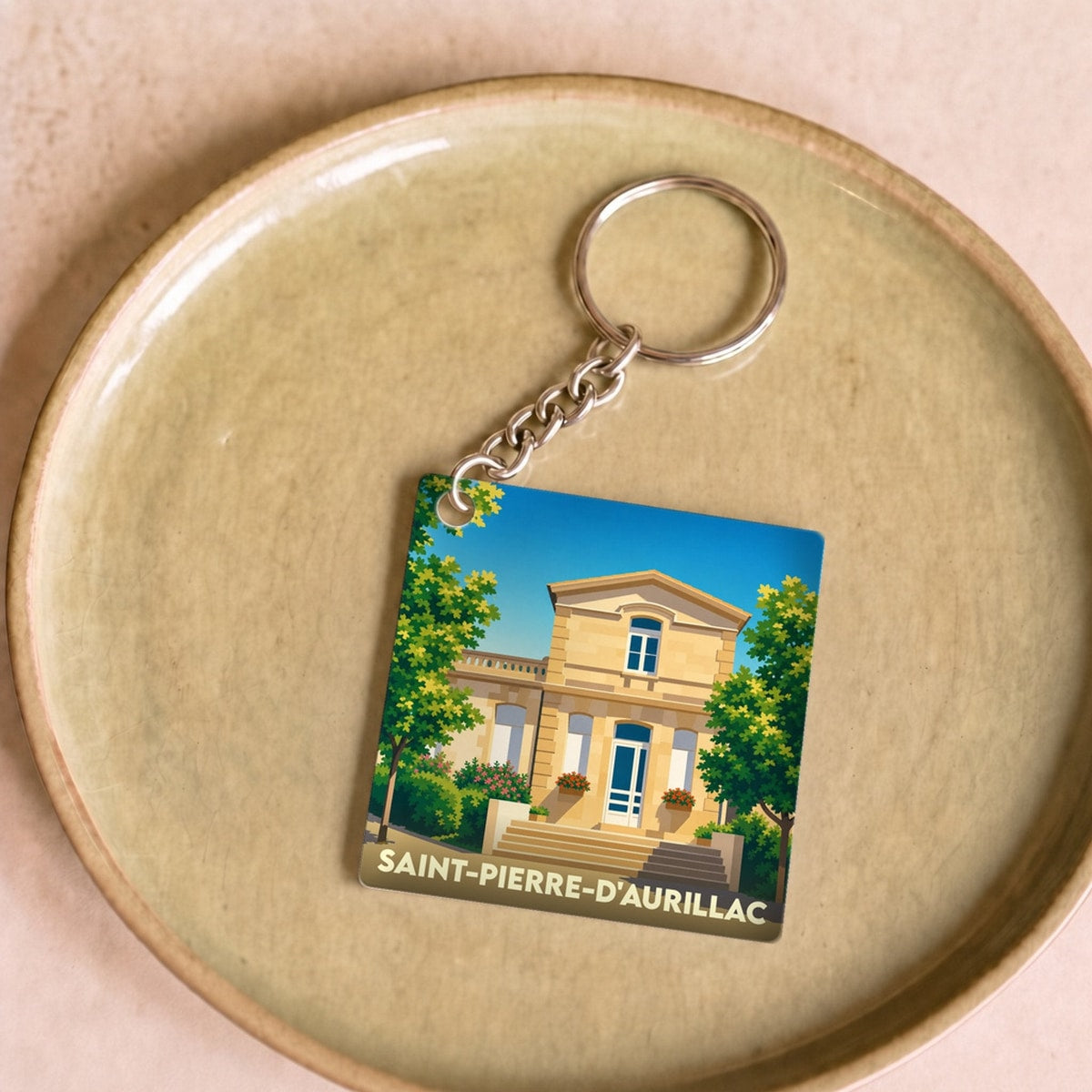 Porte-clés souvenir de la ville de Saint-Pierre-d'Aurillac avec une illustration stylisée d'un bâtiment historique.