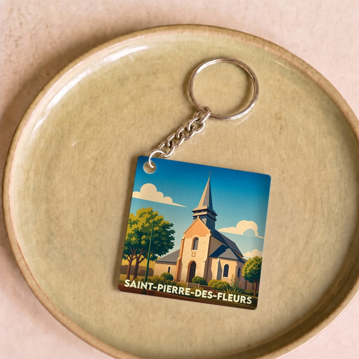 Porte-clés souvenir de la ville de Saint-Pierre-des-Fleurs avec une illustration stylisée de son église.
