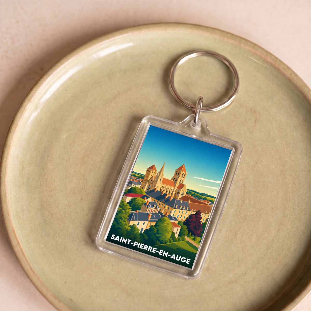 Porte-clés souvenir de la ville de Saint-Pierre-en-Auge avec une illustration stylisée.