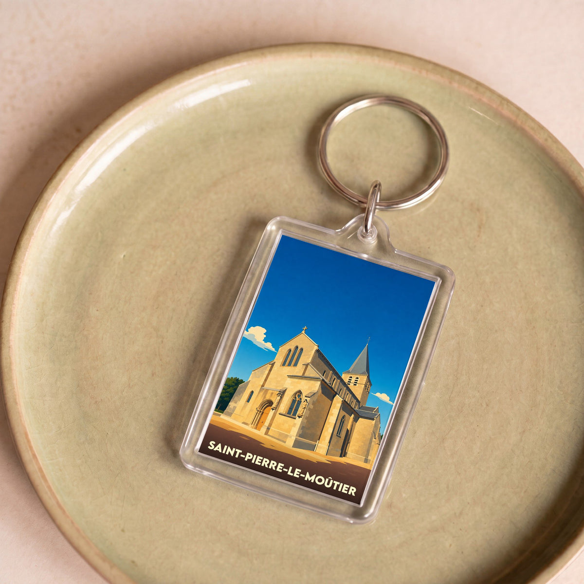Porte-clés souvenir de la ville de Saint-Pierre-le-Moûtier avec une illustration stylisée de son église.