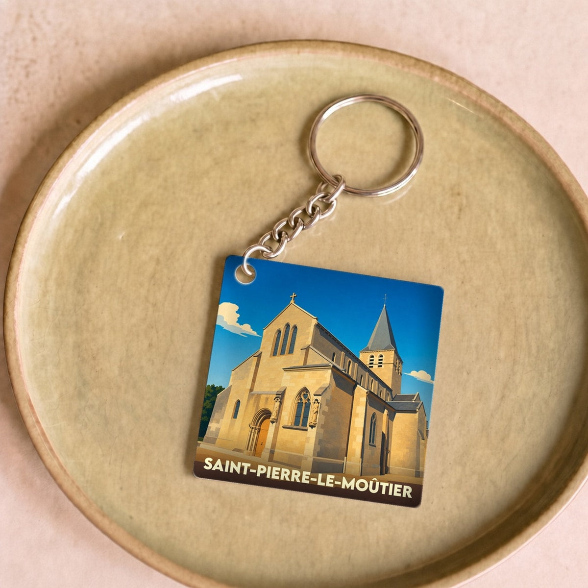 Porte-clés souvenir de la ville de Saint-Pierre-le-Moûtier avec une illustration stylisée de son église.