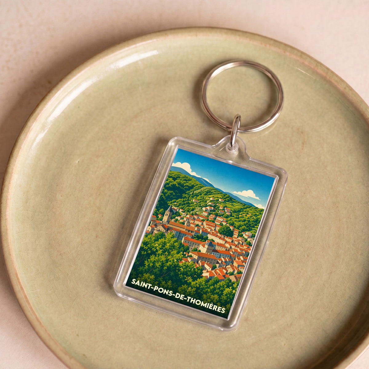 Porte-clés souvenir de la ville de Saint-Pons-de-Thomières avec une illustration paysagère stylisée.