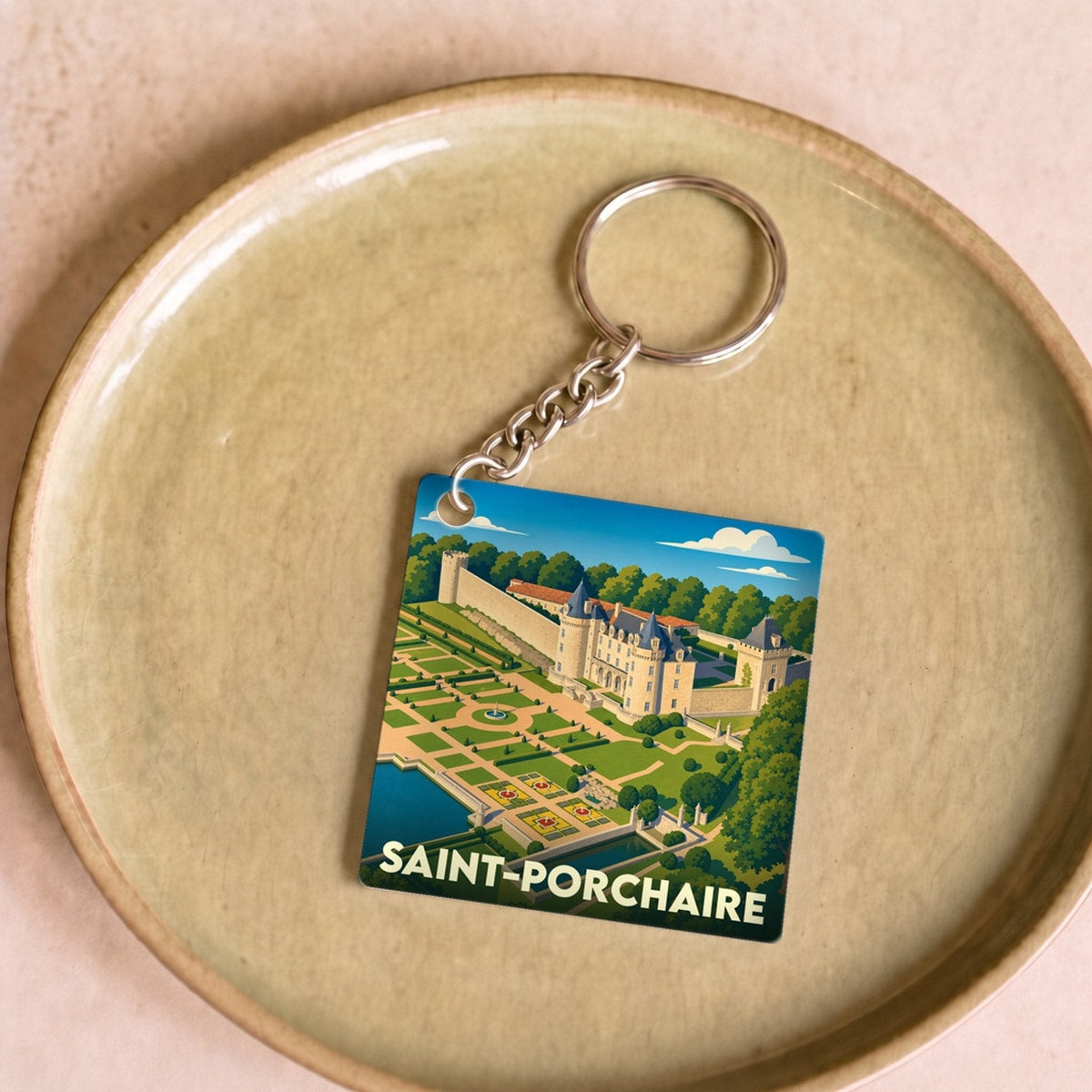 Porte-clés souvenir de la ville de Saint-Porchaire avec une illustration stylisée de son château et de ses jardins.