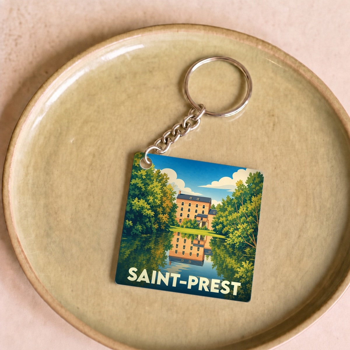 Porte-clés souvenir de la ville de Saint-Prest avec une illustration stylisée d'un manoir se reflétant dans l'eau.