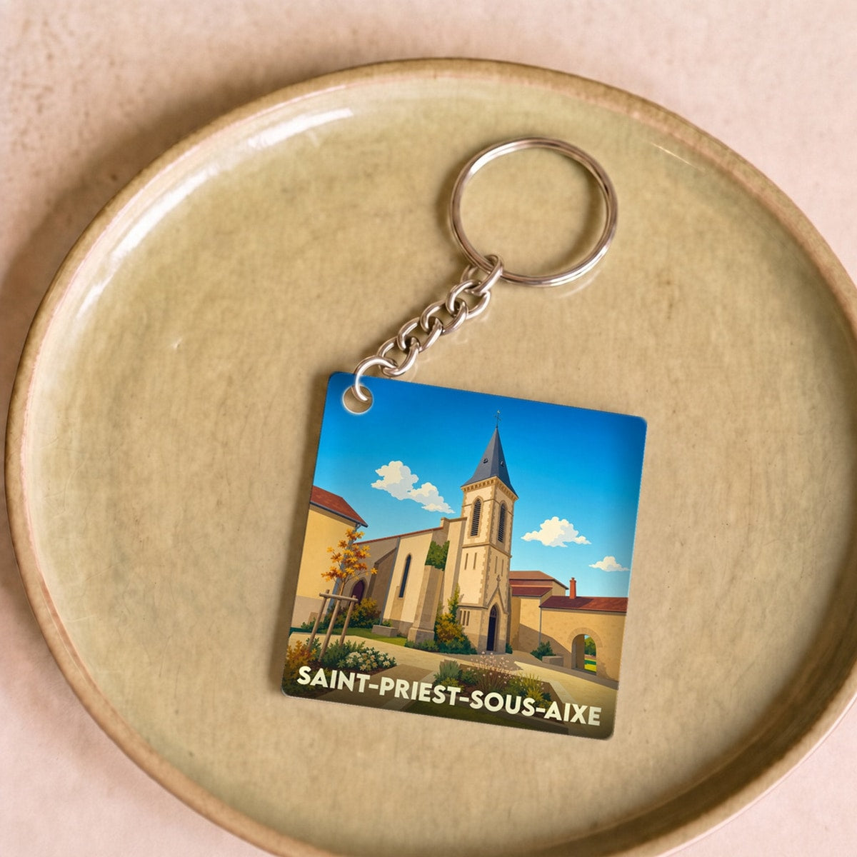 Porte-clés souvenir de la ville de Saint-Priest-sous-Aixe avec une illustration stylisée.
