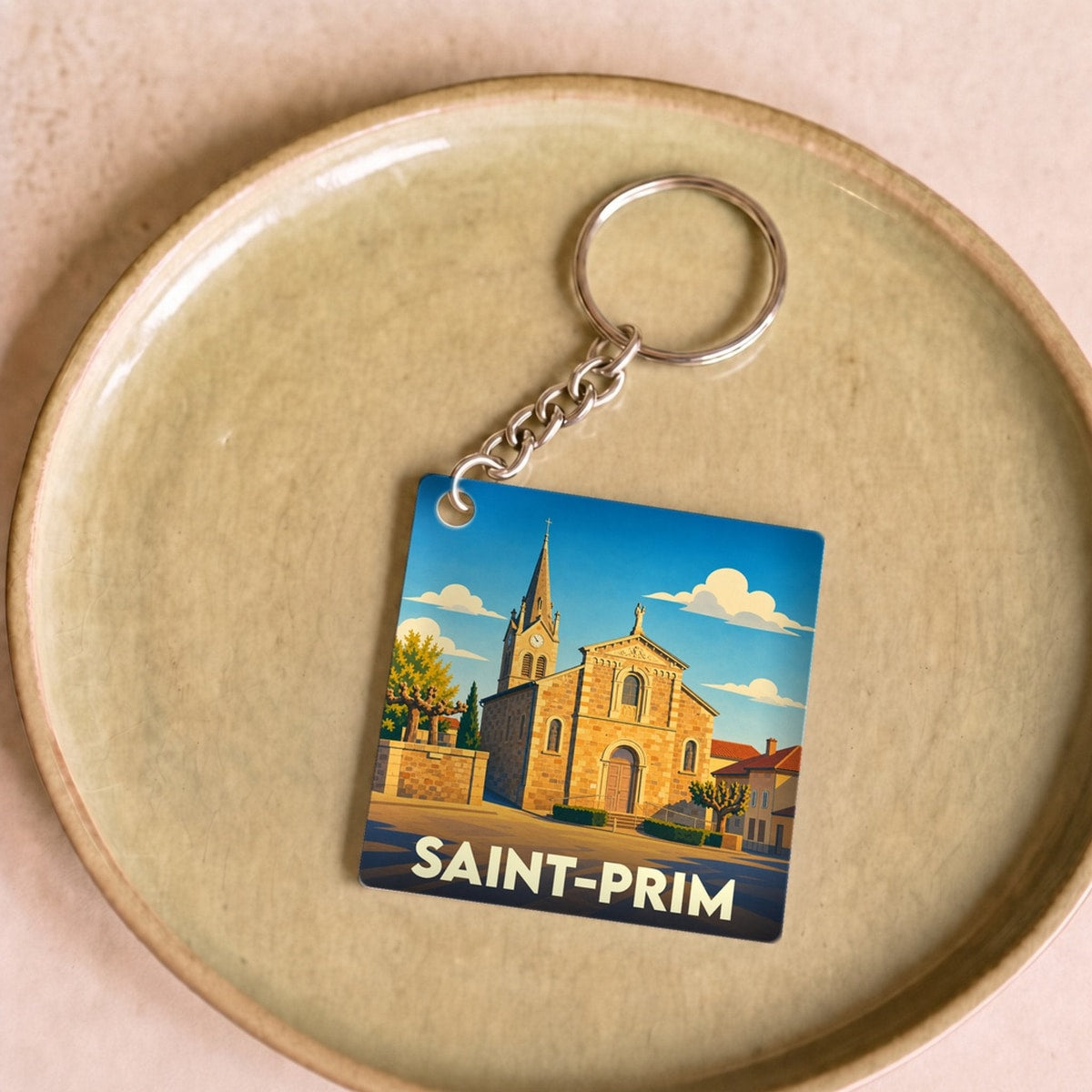 Porte-clés souvenir de la ville de Saint-Prim avec une illustration stylisée de son église.