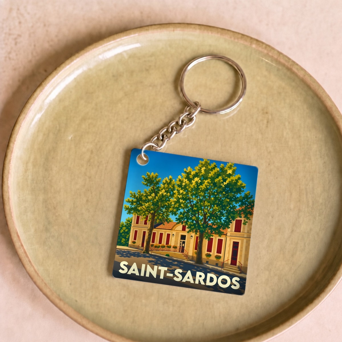 Porte-clés souvenir de la ville de Saint-Sardos avec une illustration stylisée.