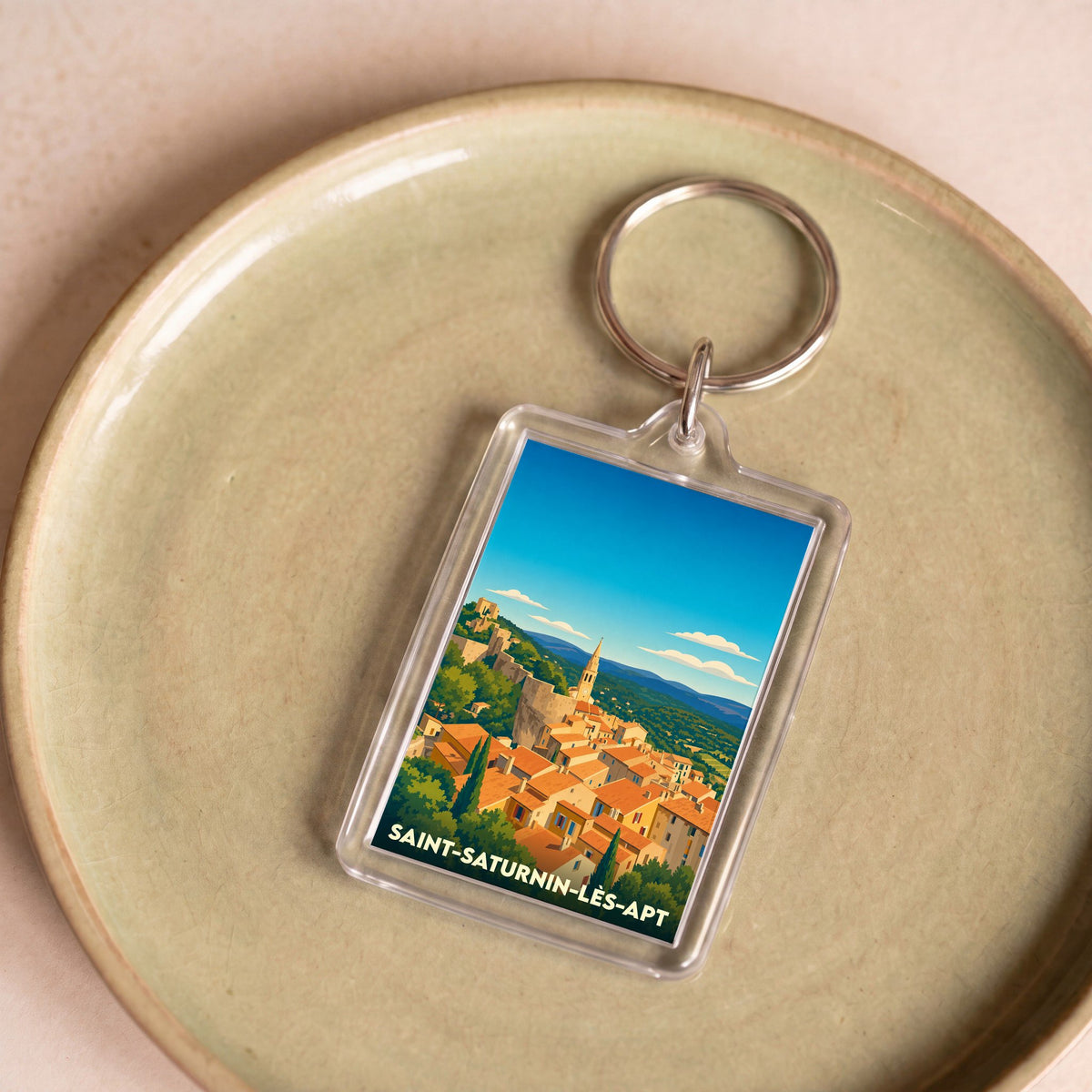 Porte-clés souvenir de la ville de Saint-Saturnin-lès-Apt avec une illustration stylisée.