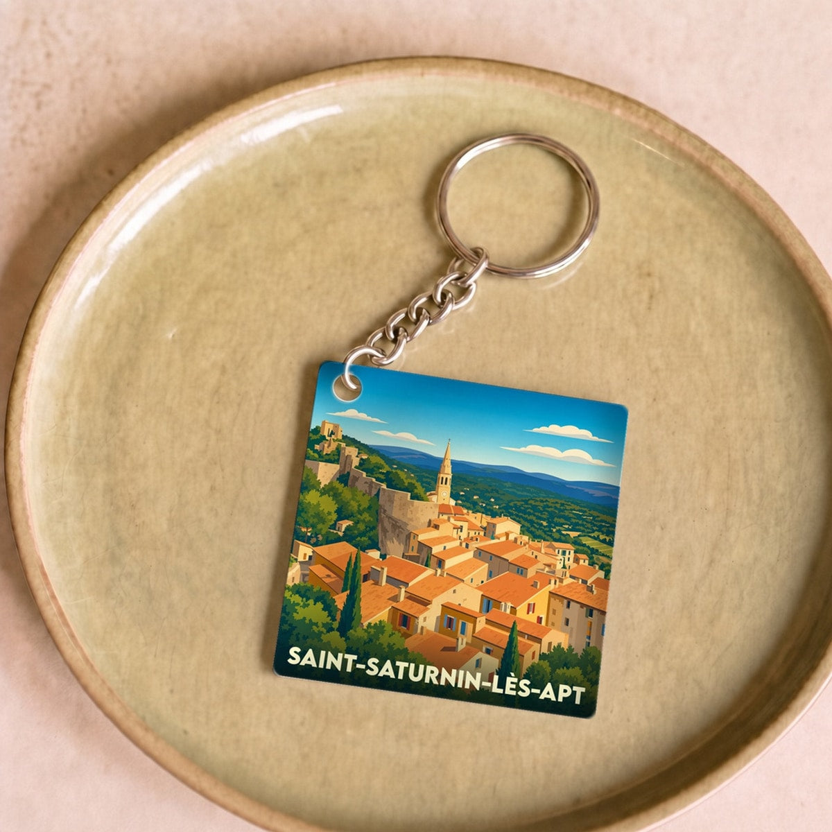 Porte-clés souvenir de la ville de Saint-Saturnin-lès-Apt avec une illustration stylisée.