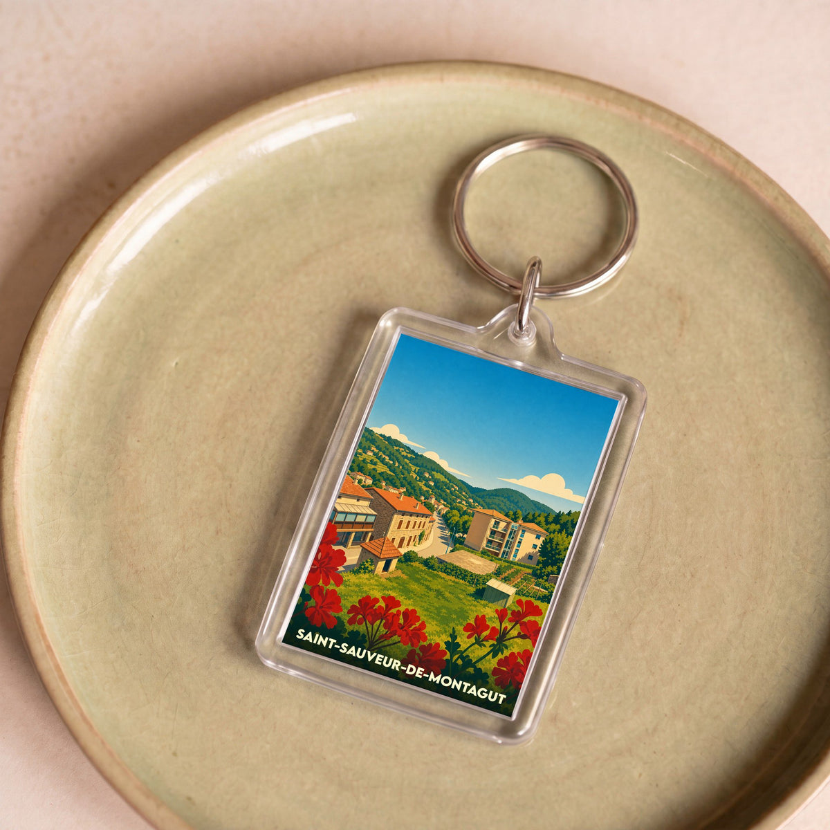 Porte-clés souvenir de la ville de Saint-Sauveur-de-Montagut avec une illustration stylisée de ses paysages.