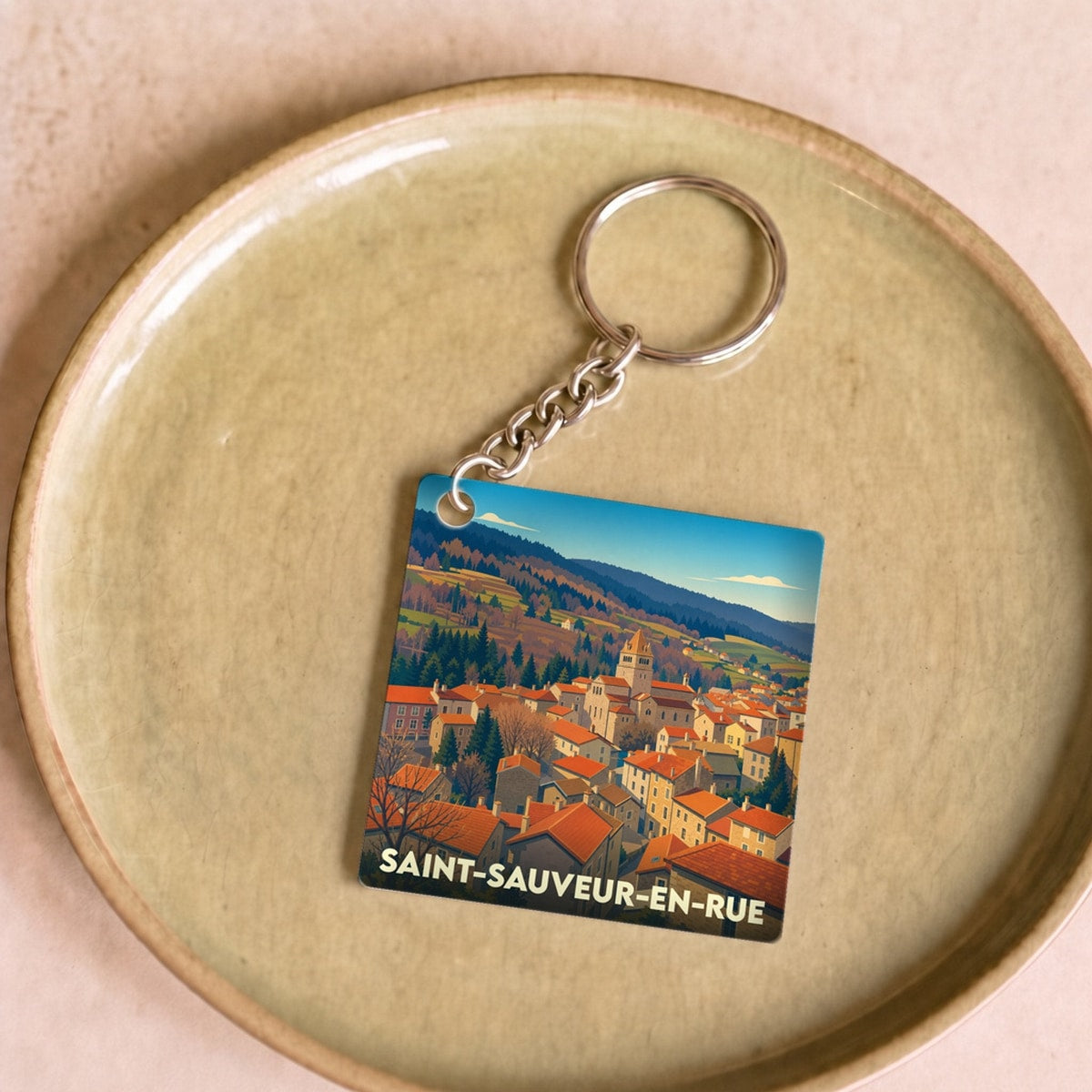 Porte-clés souvenir de la ville de Saint-Sauveur-en-Rue avec une illustration stylisée.