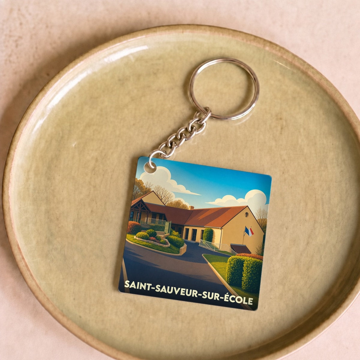 Porte-clés souvenir de la ville de Saint-Sauveur-sur-École avec une illustration stylisée.