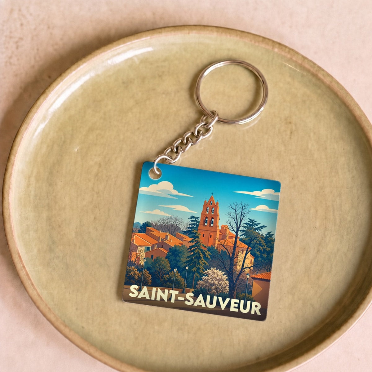 Porte-clés souvenir de la ville de Saint-Sauveur avec une illustration stylisée.