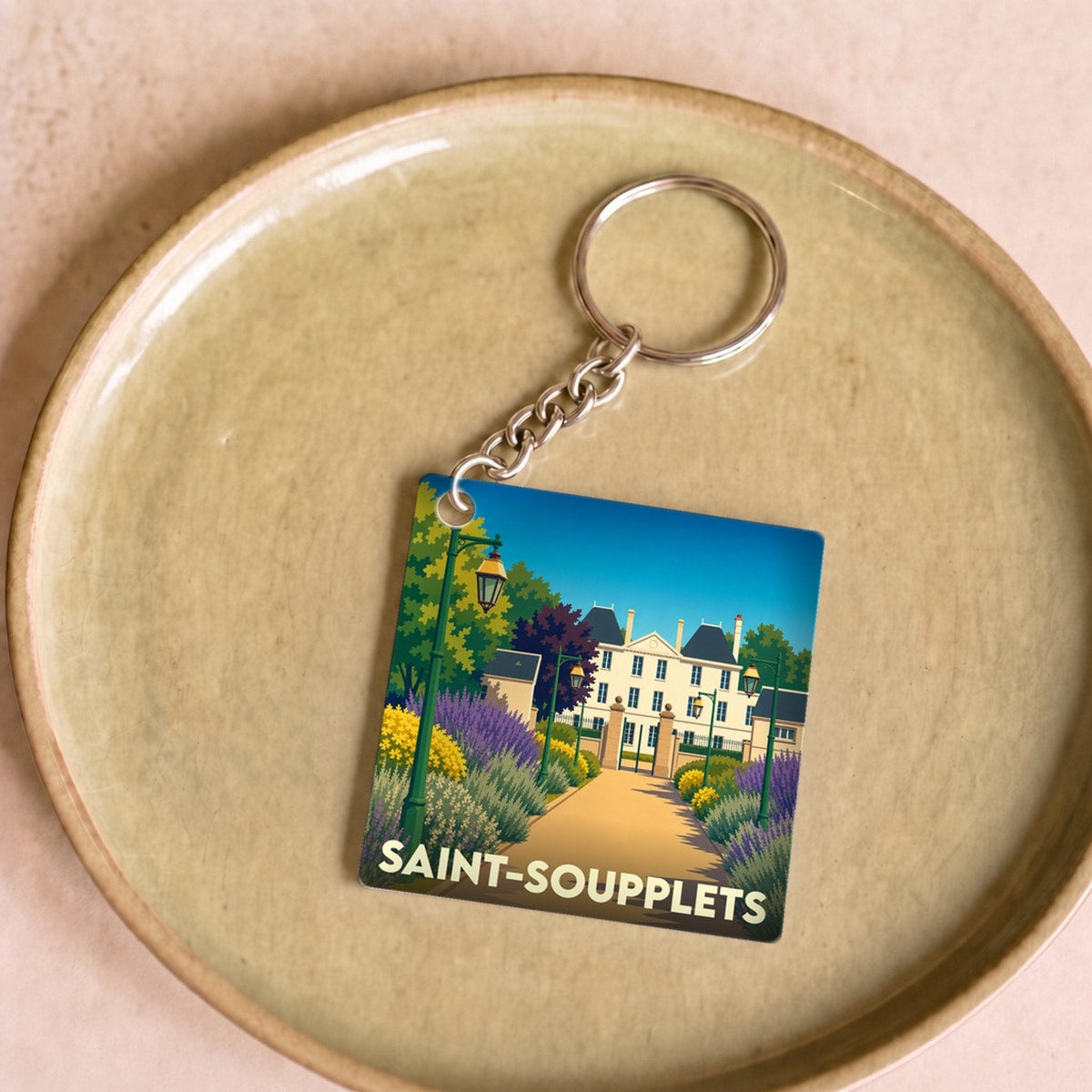 Porte-clés souvenir de la ville de Saint-Soupplets avec une illustration stylisée d'un château et de jardins.