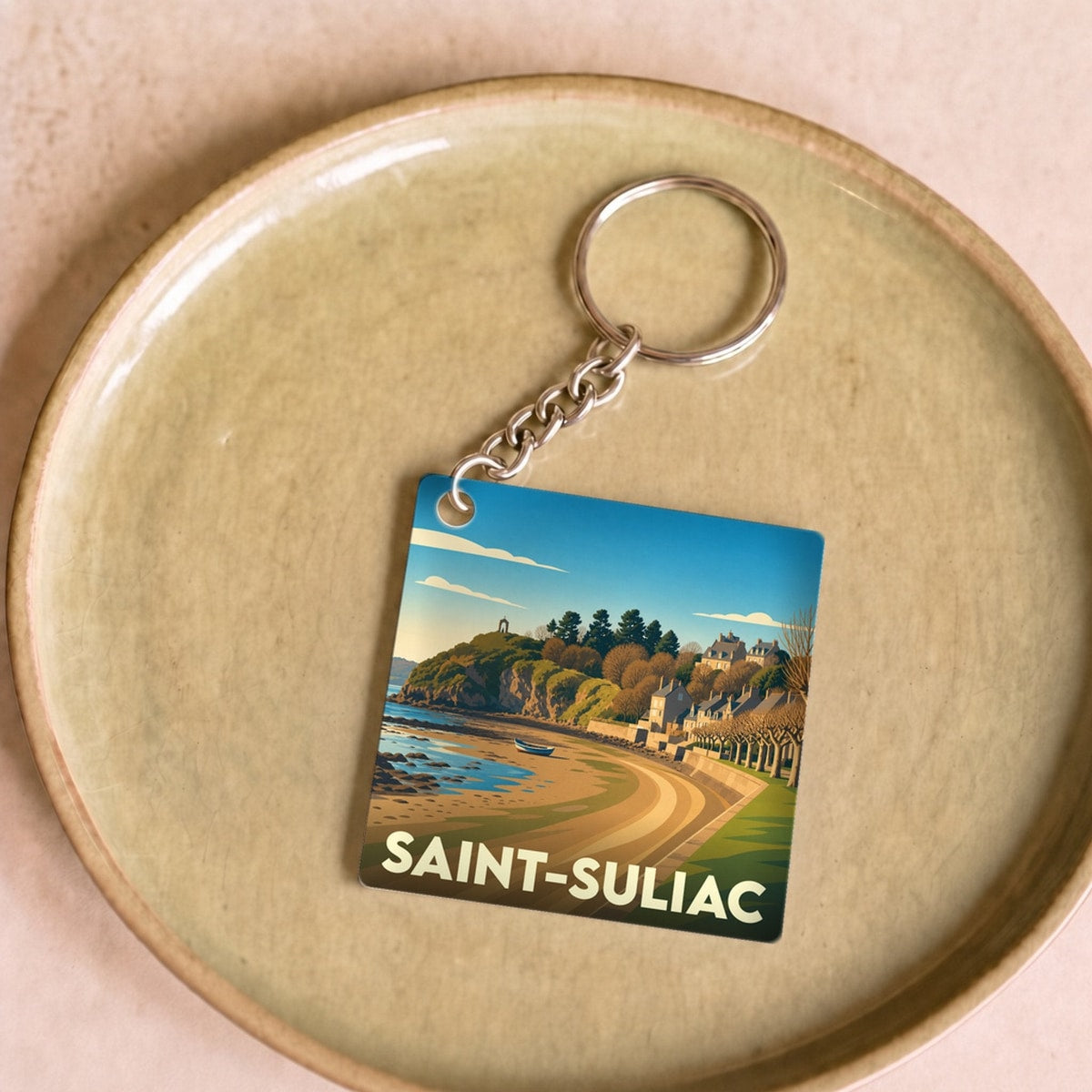 Porte-clés souvenir de la ville de Saint-Suliac avec une illustration stylisée d'un paysage côtier breton.